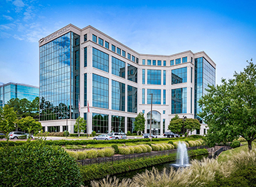 Bottle of Home Armor Outdoor Cleaner connected to water hose and sprayed along exterior of a home.